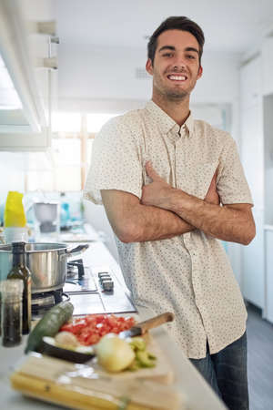 This kitchen is my domain. Portrait of a happy young man posing in his kitchen at home.の写真素材