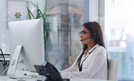 Communicating with her clients via email and call. Shot of a young businesswoman working on a...