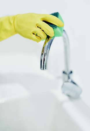 Clean till it shines. Shot of a tap being cleaned with a sponge.