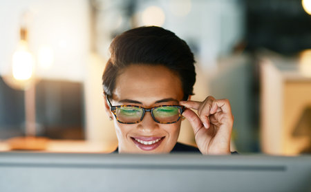 Her ambition is unfaltering. Shot of a young businesswoman working late on a computer in an office.の写真素材