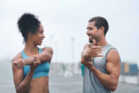 Working on becoming stronger and healthier together. Shot of two sporty young people stretching while exercising outdoors.の写真素材