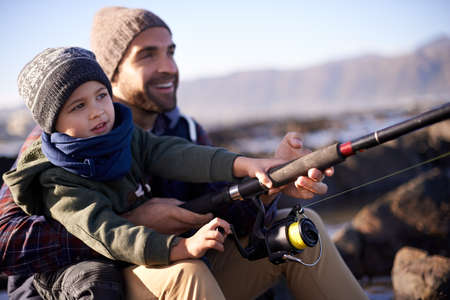 These fishes stand no chance. Shot of a loving father and son fishing by the sea.