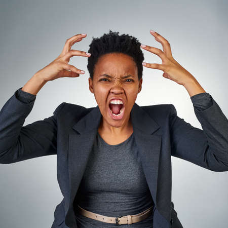 This is madness. Portrait of an angry businesswoman yelling against a grey background.の写真素材