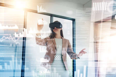 Shes in control of the future of her business. Shot of a young businesswoman wearing a VR headset while connecting to a user interface.の写真素材