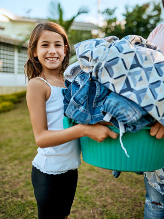 Happy to help mom out with the laundry. Portrait of a mother and daughter hanging up laundry together outside.の写真素材
