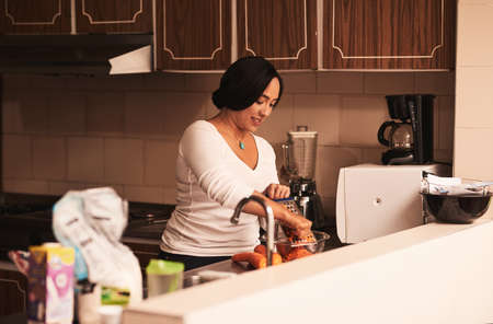 Time to bake some awesome cupcakes. Shot of a cheerful young woman baking cupcakes and grating carrots inside of a kitchen at home.の写真素材