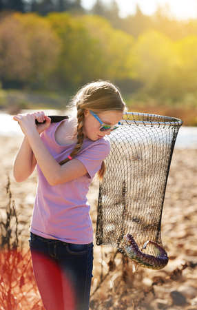 The one that didnt get away.... Shot of a young girl looking at the fish she caught with her net.の写真素材