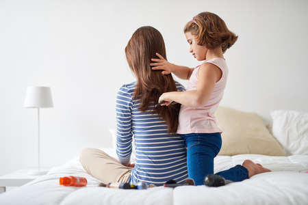 I wish I had long hair like you, mommy. Shot of a little girl brushing her mothers hair in the bedroom.の写真素材