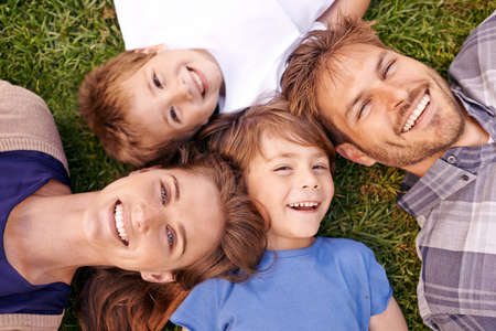 Love makes a family. Portrait of a loving family lying on the grass together.の写真素材