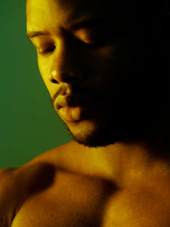 Shirtless in the shadows. Shot of a handsome young man posing topless in studio.