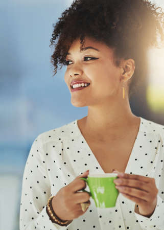 Optimism is key in setting up a new business. Cropped shot of a young designer having coffee in her office.の写真素材