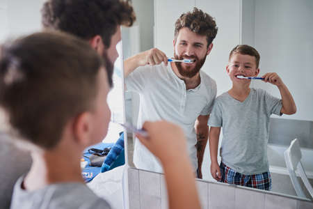 Start good oral habits early. Shot of a father and his little son brushing their teeth together in the bathroom at home.の写真素材