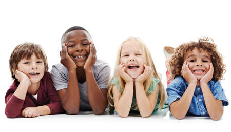 Welcome to the kids only zone. Studio shot of a group of young friends lying on the floor together against a white background.の写真素材