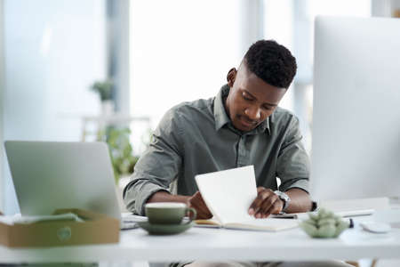 Let me make a note of that. Shot of a young businessman working on a computer in an office.の写真素材