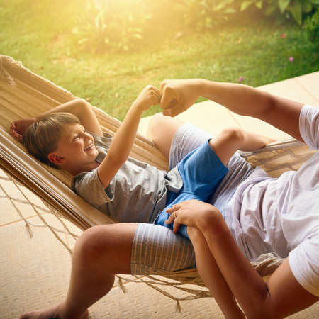 Daddys always got your back my boy. Cropped shot of a father and his adorable son chilling on the hammock outside.の写真素材