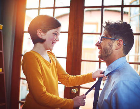 There we go - now you look perfect. Shot of a little girl adjusting her fathers tie at home.の写真素材