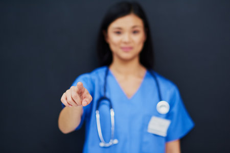 The future of medicine is here. Cropped portrait of a blurred out female nurse using a touchscreen interface while standing against a black background.の写真素材