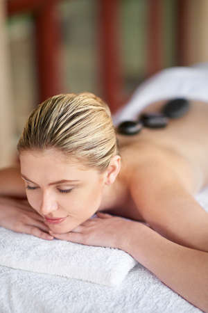 Deep relaxation. Shot of a young woman having a lastone treatment at the spa.の写真素材