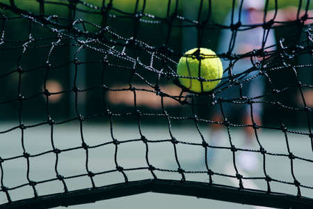 Thats a lost point. Cropped shot of a tennis ball hitting a tennis net on the court during the day.の写真素材