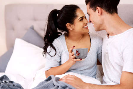 Youre the only thing thats more important than my coffee. Shot of a young couple spending quality time in bed.の写真素材