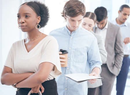 Theyre all focused on reaching their goals. Shot of a group of businesspeople waiting in line at an...