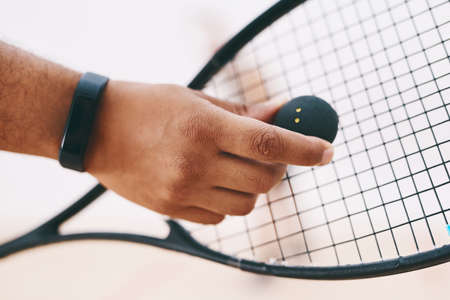 A good game starts with a good serve. Cropped shot of a man serving a ball with a racket during a game of squash.の写真素材