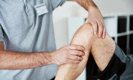 he will make the pain go away. Shot of an unrecognizable male physiotherapist helping a client with...