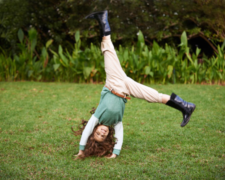 Doing cartwheels is so much fun. Shot of a cute little girl doing cartwheels on the grass.
