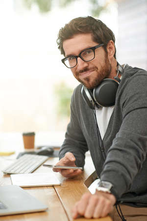 With the right tools I can get a lot done. Portrait of a young entrepreneur using a mobile phone at...