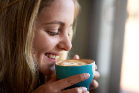 Theres nothing better than the smell of fresh-brewed coffee. Closeup shot of an attractive young woman enjoying a cappuccino in a coffee shop.の写真素材