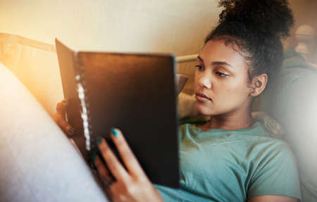 Finals are fast approaching. High angle shot of a young female student studying at home.
