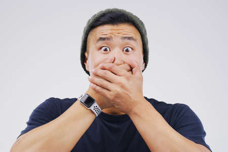 How did that happen. Studio shot of a young man looking shocked against a grey background.の写真素材