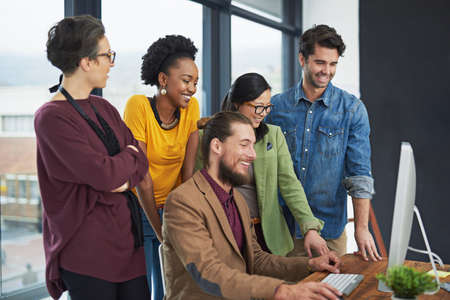 Bring on that deadline. Cropped shot of a group of creative businesspeople looking at something on a computer.の写真素材