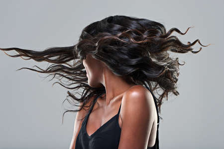 Now this is a hairstyle. Studio shot of a young woman with beautiful hair isolated on gray.の写真素材