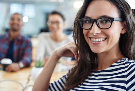 Job satisfaction...check. Shot of a young office worker sitting at her workstation in an office.の写真素材