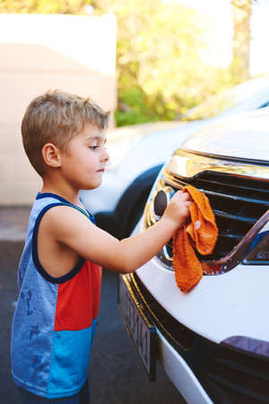 Daddy will be proud. Cropped shot of an adorable little boy washing a car outside.の写真素材