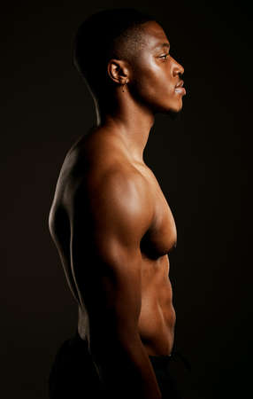 Every pound of muscle is pure man. Studio shot of a fit young man posing against a black background.の写真素材