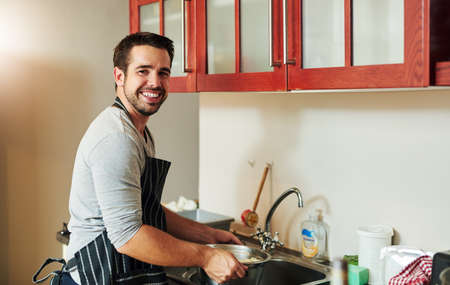 This pasta is just about ready. Cropped portrait of a handsome young man draining pasta at home.の写真素材