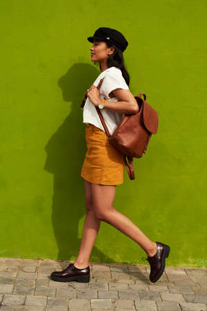 Im a woman on a mission. Full length shot of an attractive young woman walking against a green background during a day out in the city.の写真素材