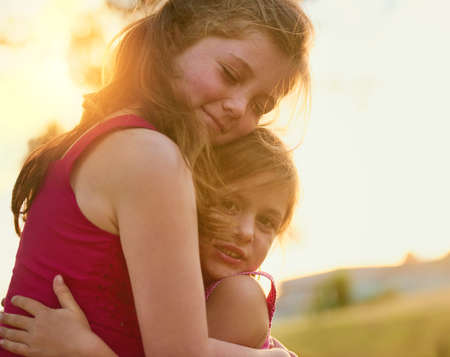 Sisters and friends. Shot of a sweet little girl giving her sister a hug while they play in the...