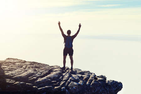 The best view comes after the hardest climb. Rearview shot of an unidentifiable young man raising...
