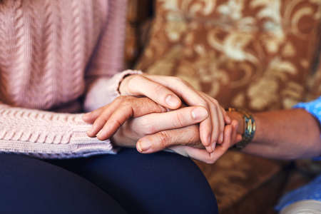 We in this together, you are not alone. Cropped shot of unrecognizable women holding hands at home.の写真素材