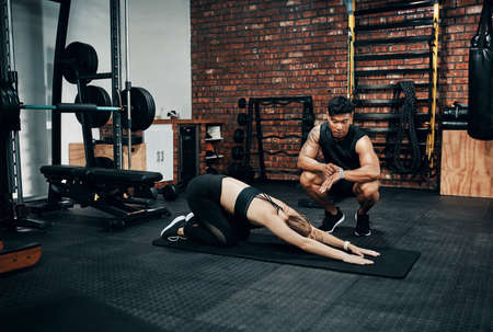 I need you to hold it for a few more seconds. Shot of a young woman working out with her personal...
