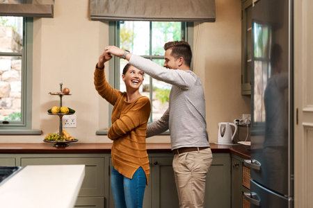 Shes forever his princess. Shot of an affectionate young couple dancing together in their kitchen at home.の写真素材