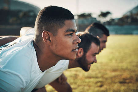 You could say theyre not here to play, but they are. Cropped shot of a group of three young rugby players lining up for a scrum on the field during the day.の写真素材