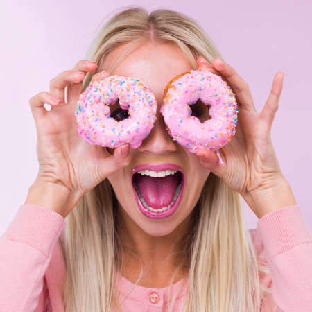 Shes going do-NUTS. Cropped shot of a woman holding donuts in front of her eyes while isolated on...