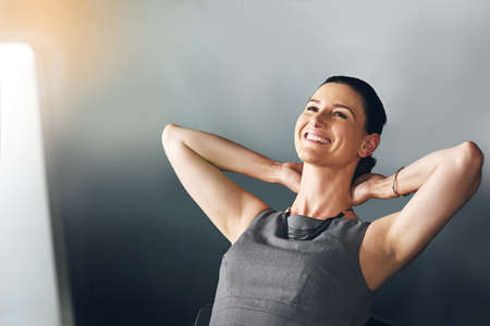 Feeling relaxed at work. Cropped shot of a businesswoman sitting with her hands behind her head in...