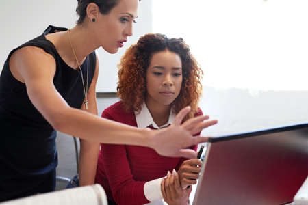 They work well together. Shot of two businesswoman working together at a computer in an office.