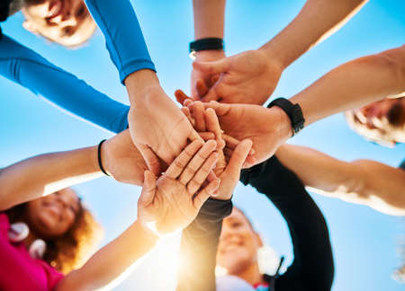 Gather around. Low angle shot of a group of young cheerful friends forming a huddle before a fitness...