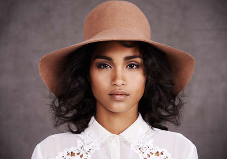 Shes not driving Miss Daisy. Cropped portrait of a stylish young woman wearing a hat standing...
